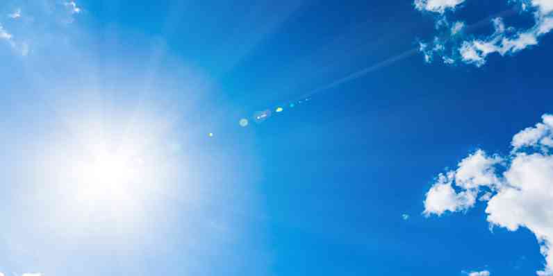Photo of a bright blue sky with clouds and rays of sun