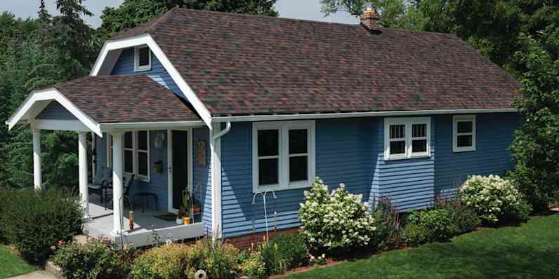 Blue craftsman style house with white windows and a beautiful new roof with brown and red tones from the Owens Corning TruDefinition Duration Series shingles.