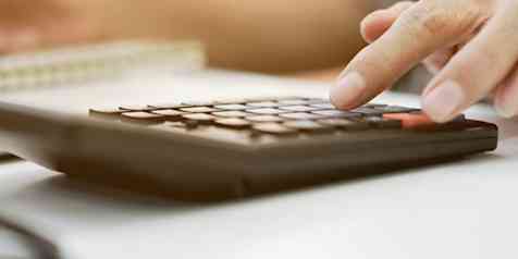 Closeup of a person's hand on a desk using a calculator