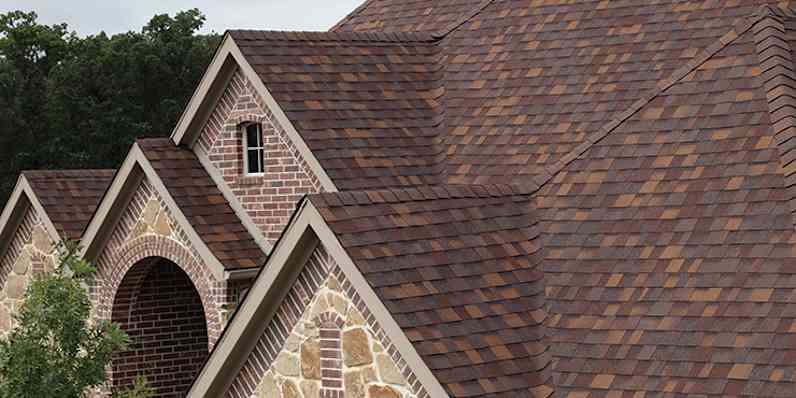 A photo of the top of a brick house with TruDefinition® Duration® Designer Shingles in Sedona Canyon