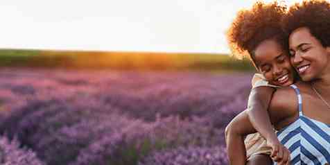 Woman holding child on her back in a field of lavender