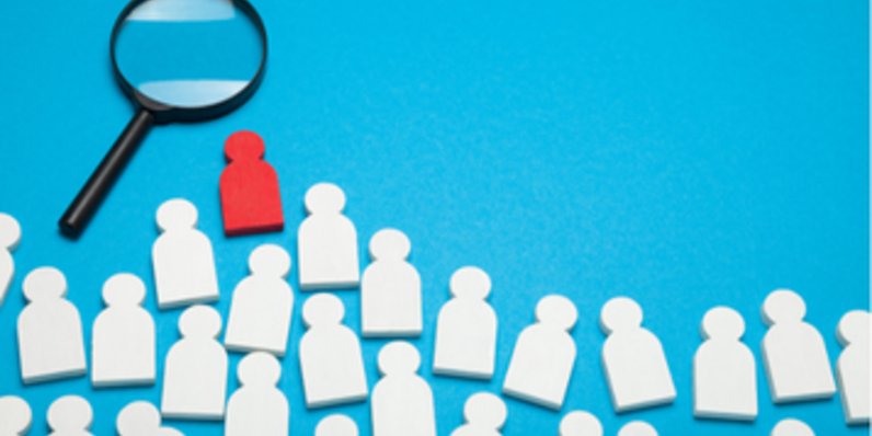Stock image of people markers and a magnifying glass against a blue background.