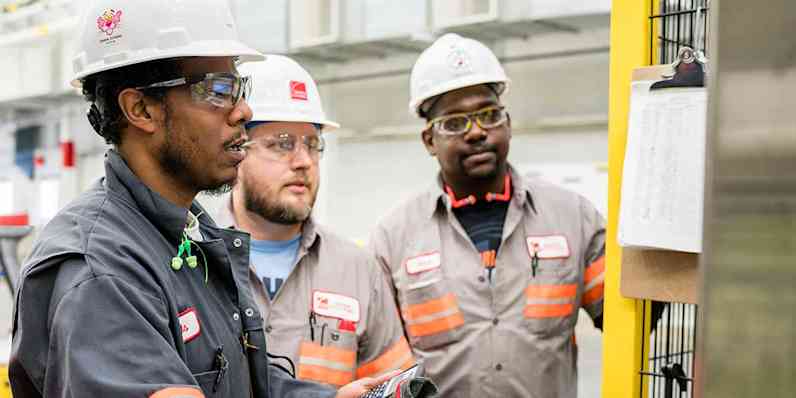 A group of OC employees in a manufacturing plant