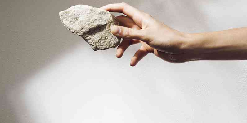 käsi, mis hoiab kivitükki