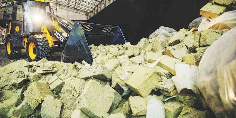 a plant worker inspecting a piece of stone wool