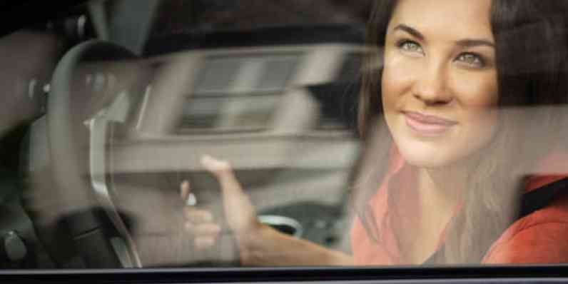 Woman gawking out the car window while driving by a house with Owens Corning shingles on the roof.