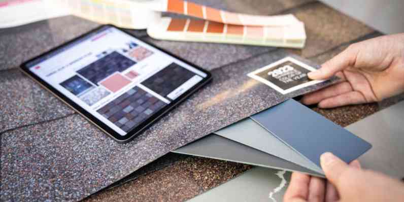 A homeowner comparing siding colors with an Owens Corning Shingle Poster to while reviewing shingles on an iPad.