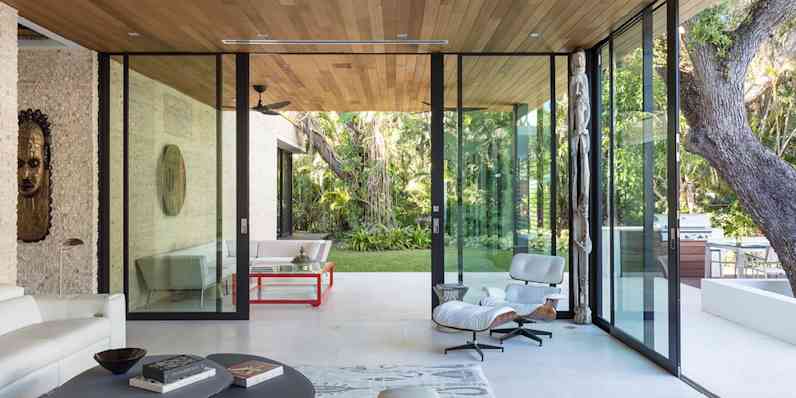 Modern sitting room with two walls completely made from glass doors that are open to a patio