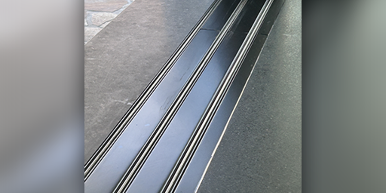 Close-up view of Fleetwood flush subfloor solution showing recessed sliding door tracks integrated into dark stone flooring for a seamless indoor-outdoor transition.