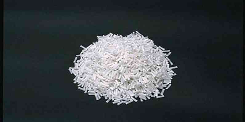 Pile of chopped white fibers displayed on a dark, smooth background.