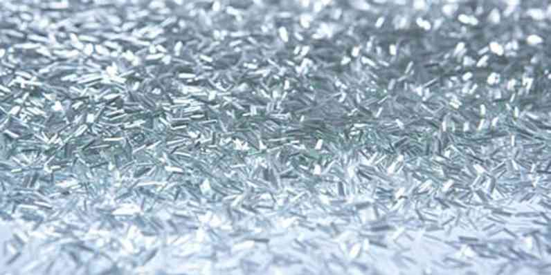 Close-up of loose, shiny chopped fibers scattered across a reflective surface.