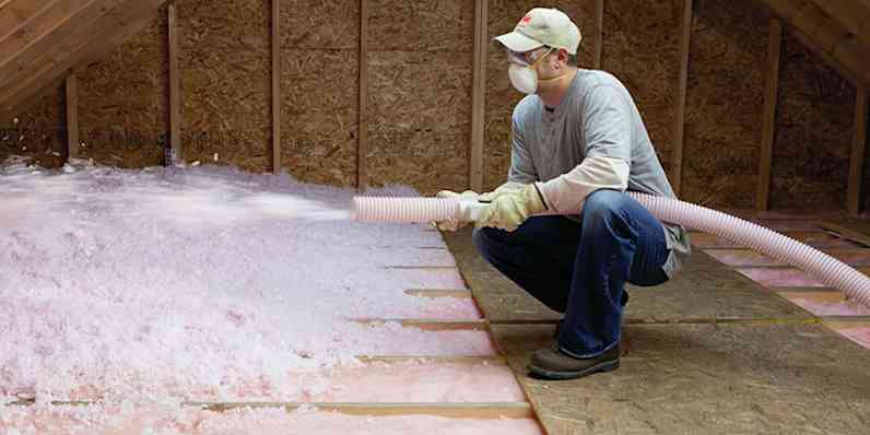 A contractor blowing in loosefill insulation in an attic