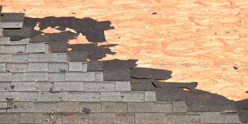 Closeup photo of a roof with old shingles being torn off