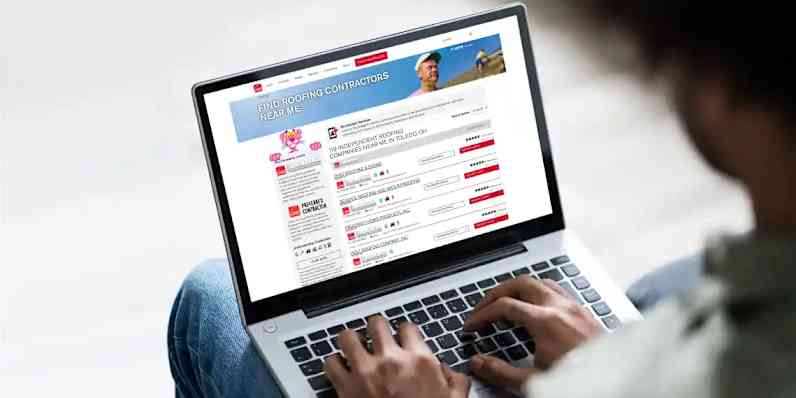 Photo of a person using a laptop with Owens Corning Find a Contractor web page on the screen