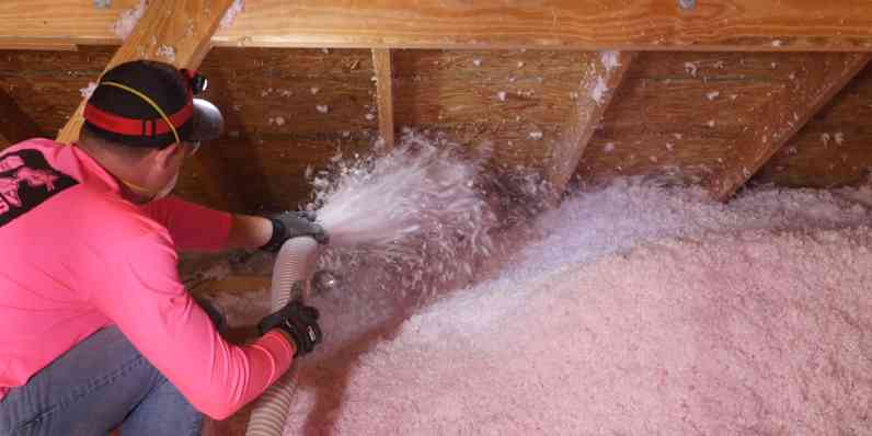 Close-up of insulation being blown in around the edge of an attic