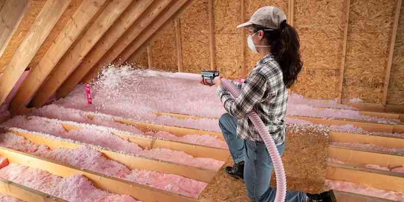 Homeowner blowing in AttiCat® Insulation in an attic