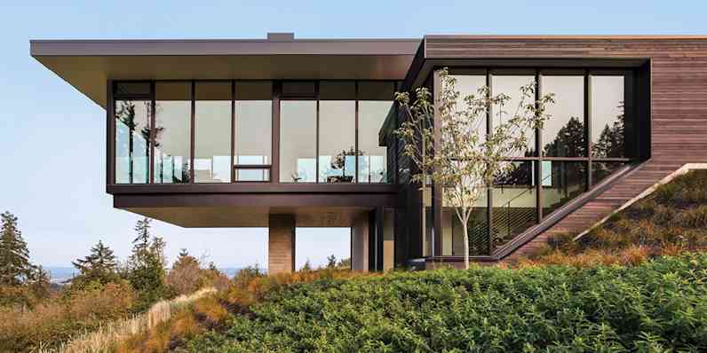Exterior view of a modern building on a hillside with glass doors and windows.