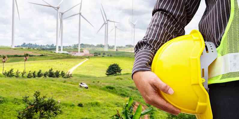photo of wind turbines with a worker in the foreground