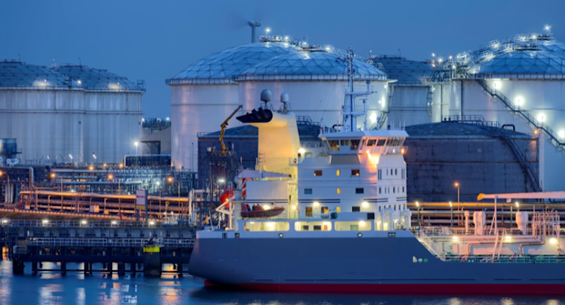 A ship docked at a site with storage tanks