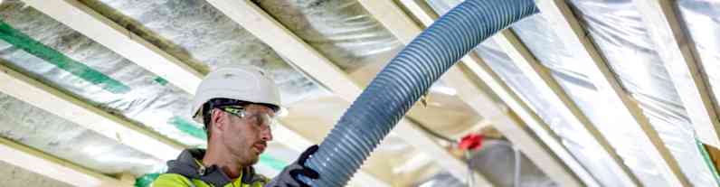 en mand i beskyttelsestøj efterisolerer loftsbjælkerne