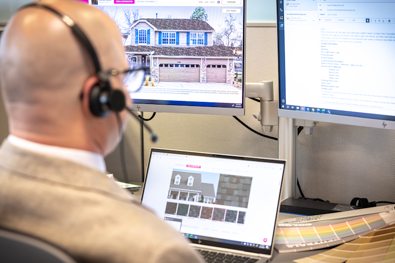 Owens Corning Roofing color consultant sitting at a desk with a headset on, looking at home photos, shingle swatch colors and pantone swatch chips.