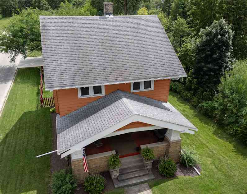 An orange sided two story house with older gray shingles