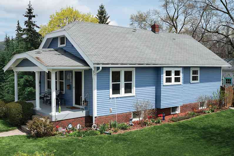 A light blue house with a porch and a white roof.