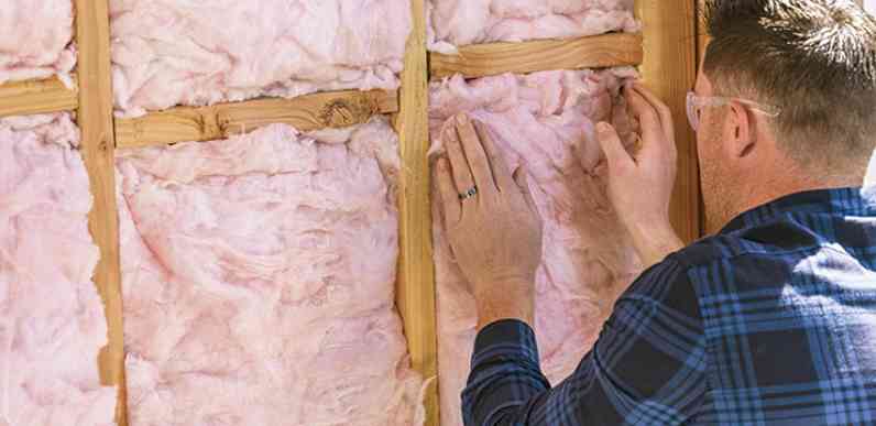 Un installateur a poussé un isolant rose dans une cavité murale.
