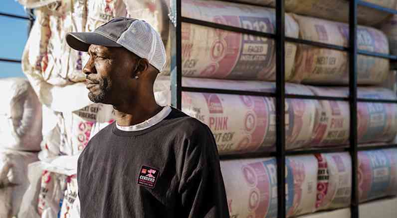 A man stands in front of a truck full of fiberglass