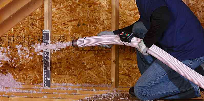 Photo of a contractor blowing in Fiberglass insulation