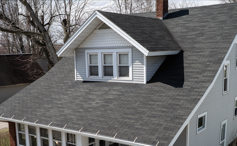 Una casa azul que parece deteriorada con tejas grises en el techo.