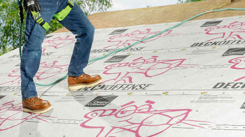 Photo of a contractor on a roof installing DeckDefense® High Performance Synthetic Roof Underlayment