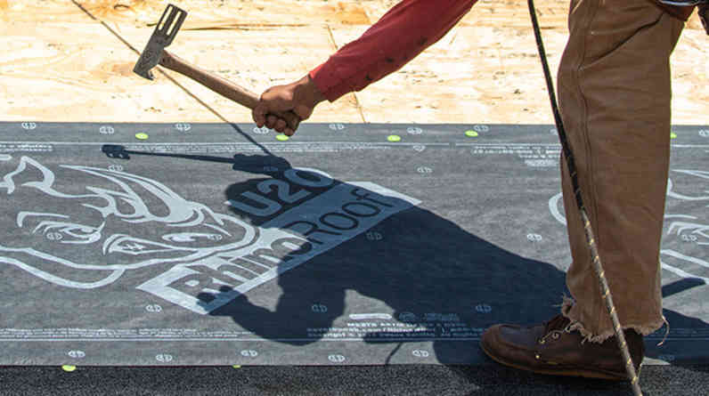 Photo of a contractor on a roof installing  RhinoRoof® U20 Synthetic Roofing Underlayment