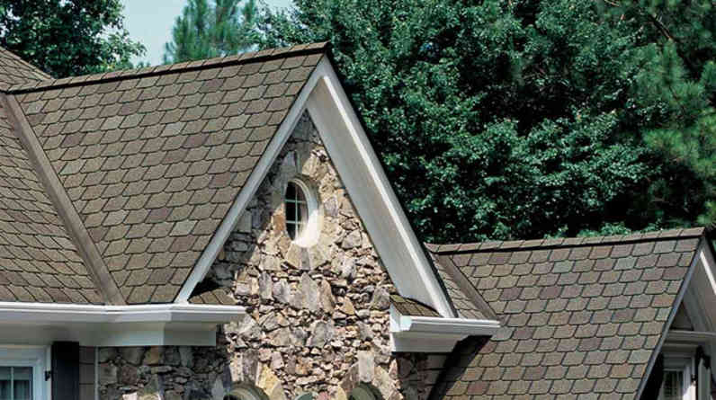 Photo of a tan roof with Berkshire® Hip & Ridge Shingles set against a blue sky and vibrant green trees