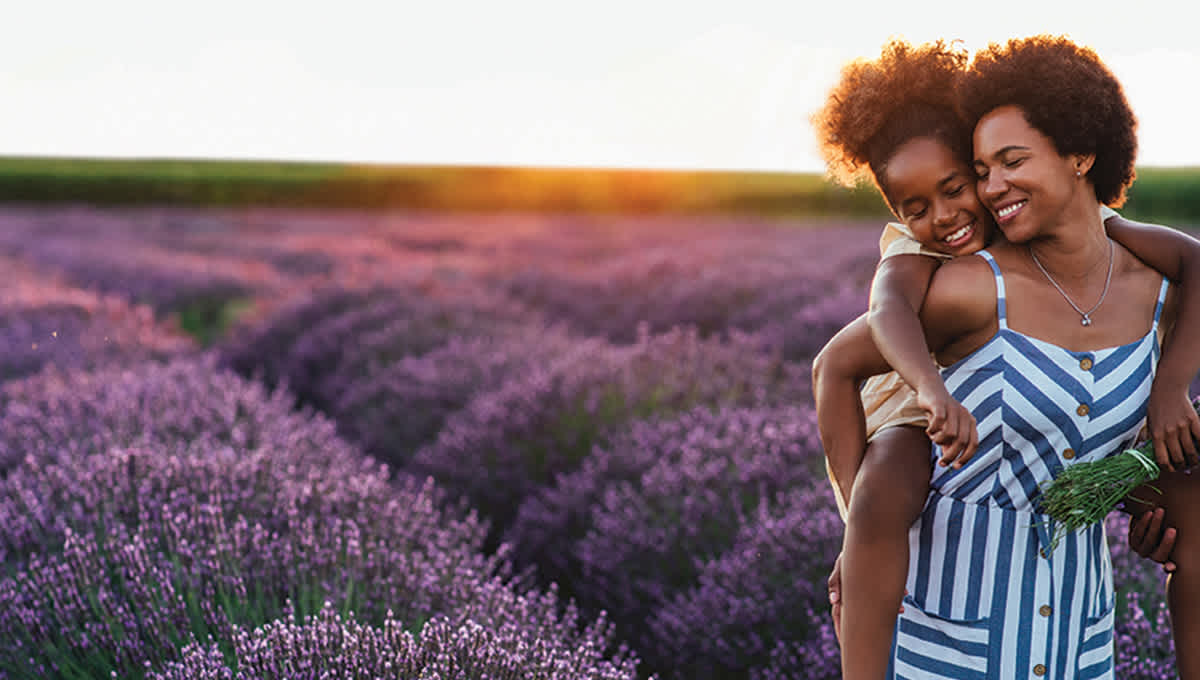 Woman holding child on her back in a field of lavender