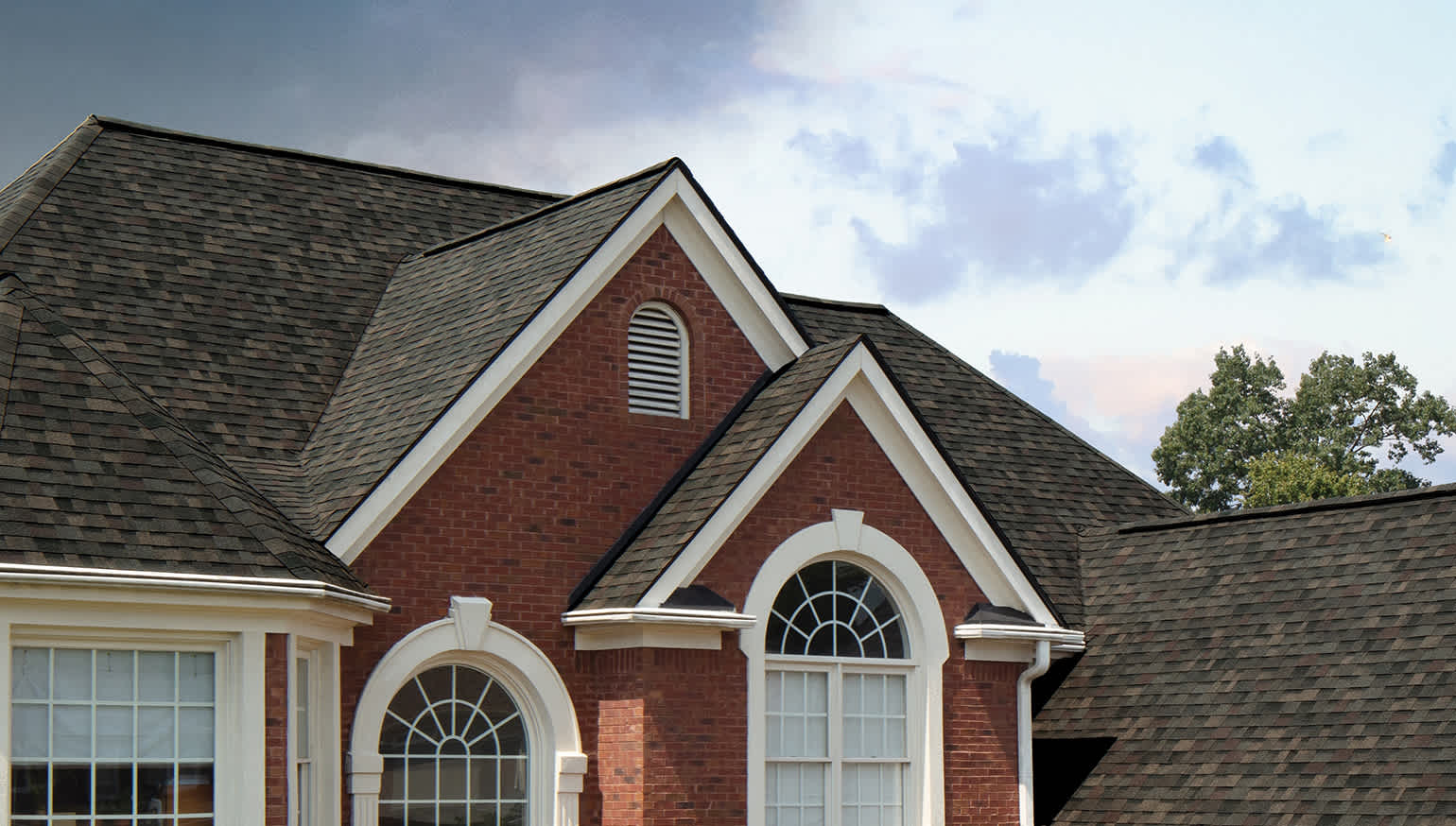 House with red brick, white trim and Black Sable roofing shingles