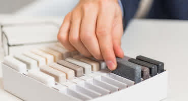 Close up view of hand sorting through material samples in a box