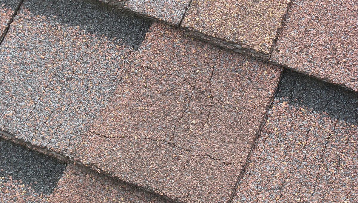 Close up of brown shingles with hairline cracks visible