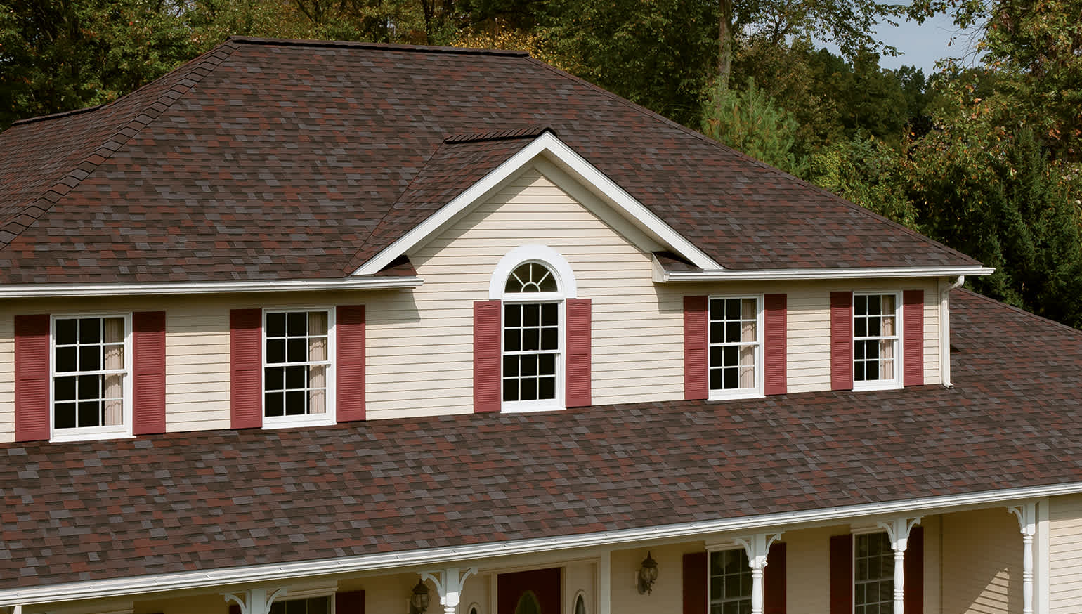 House with light tan siding, rusty red shutters, and Merlot roofing shingles