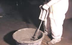 En person blander limet i en bøtte.