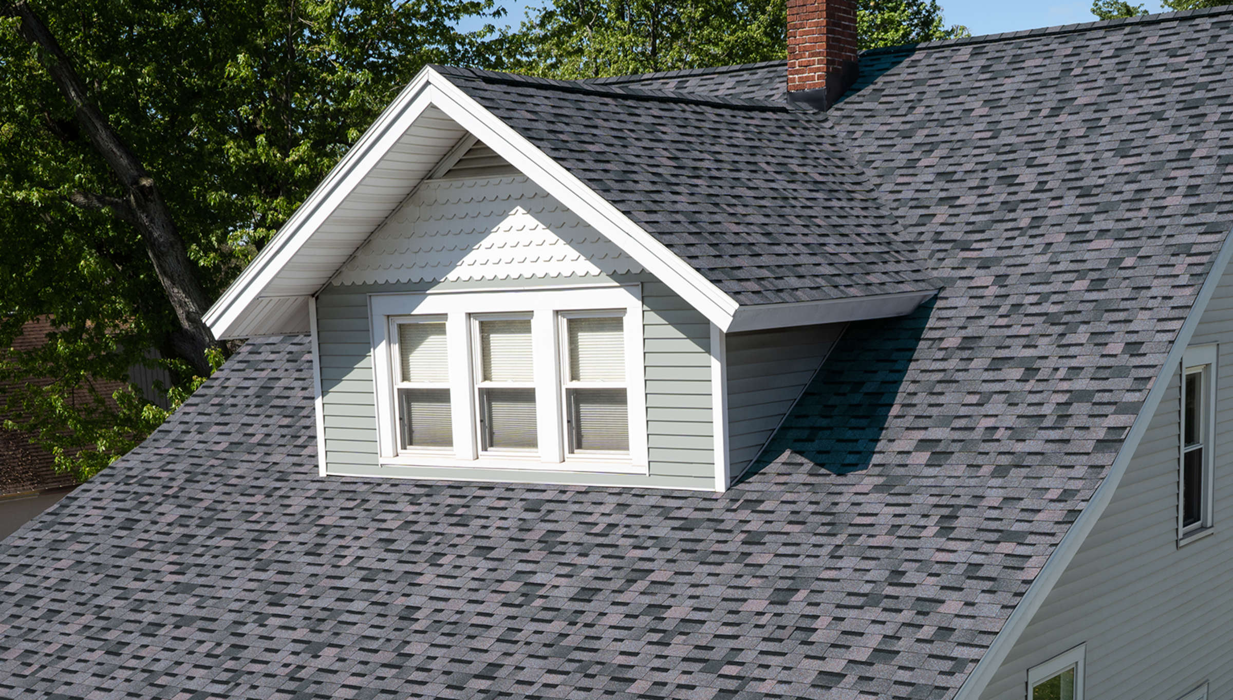House with light grey siding, white scalloped accents, and Midnight Plum roofing shingles