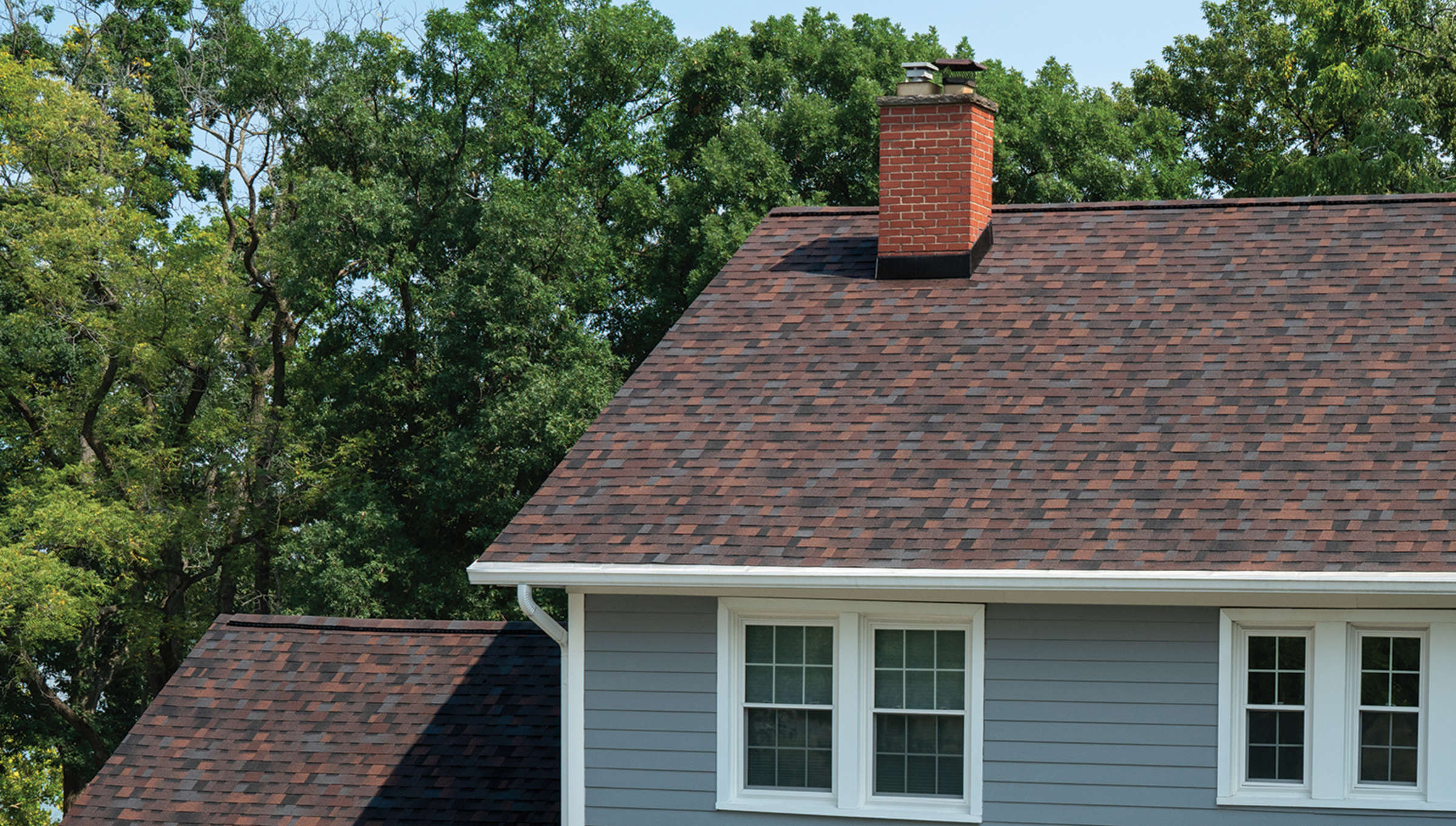House with grey siding, white trim and windows, and Bourbon roofing shingles