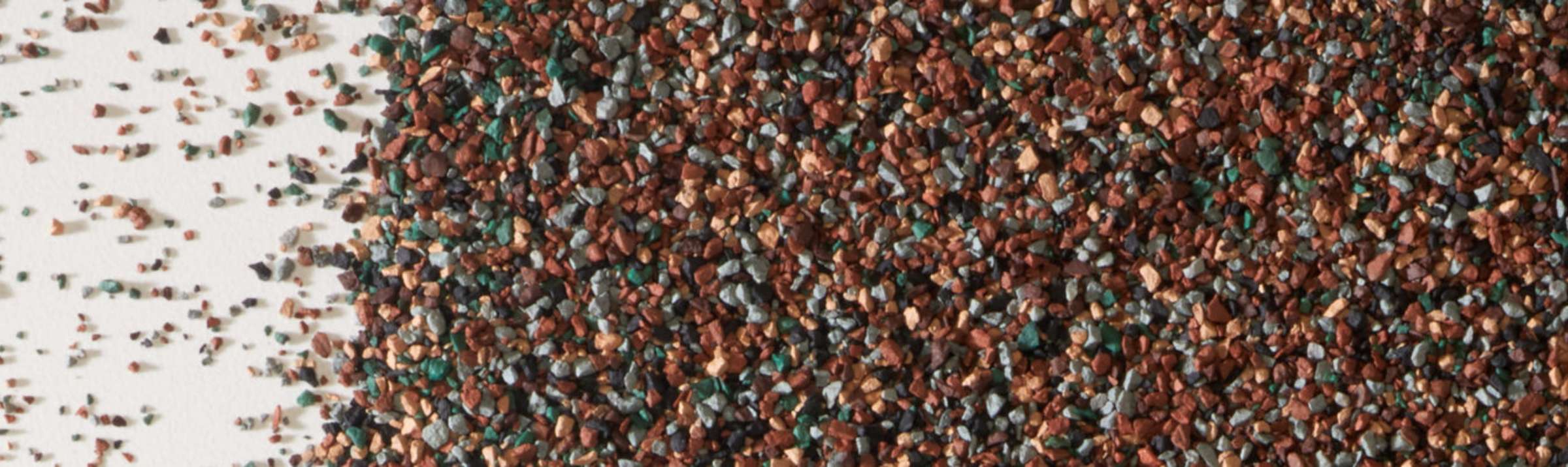 Closeup photo of shingle granules in brown, gray, green, and tan colors