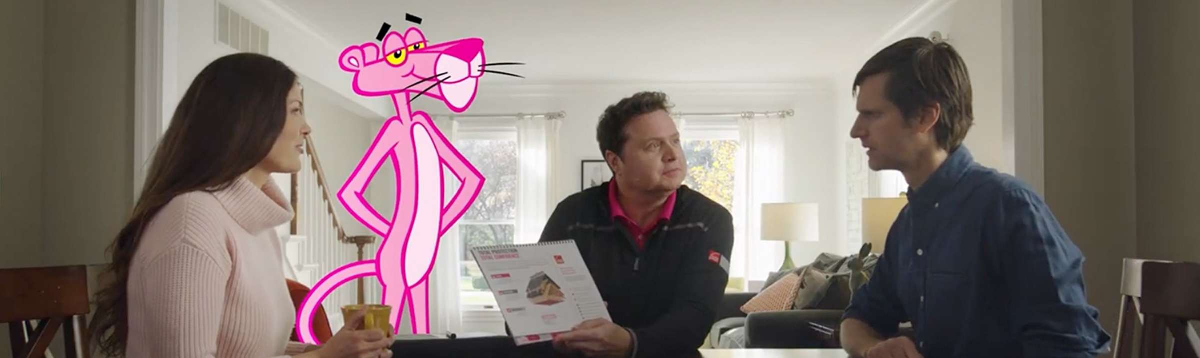 Man and woman meeting with a roofing contractor, sitting at their kitchen table with the Pink Panther standing nearby