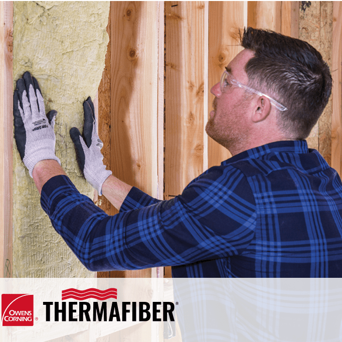 A man installing mineral wool insulation in a wall
