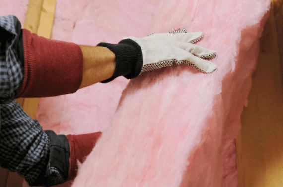 Contractor installing Owens Corning ProPink blown-in insulation into wall cavity.