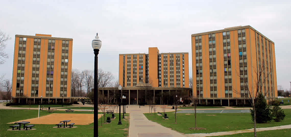 Campus view of three buildings surrounded by pathways and picnic tables