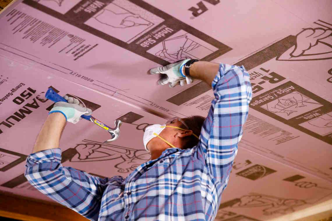 Man wearning plaid shirt installing foamular 150 foam board insulation 