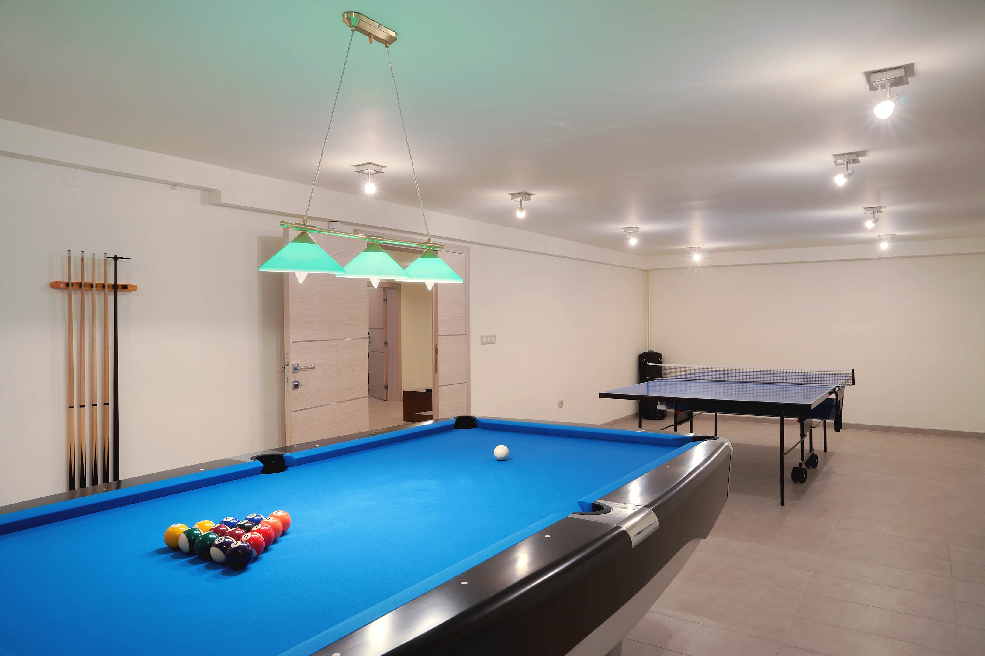A finished basement with a pool table and ping pong table