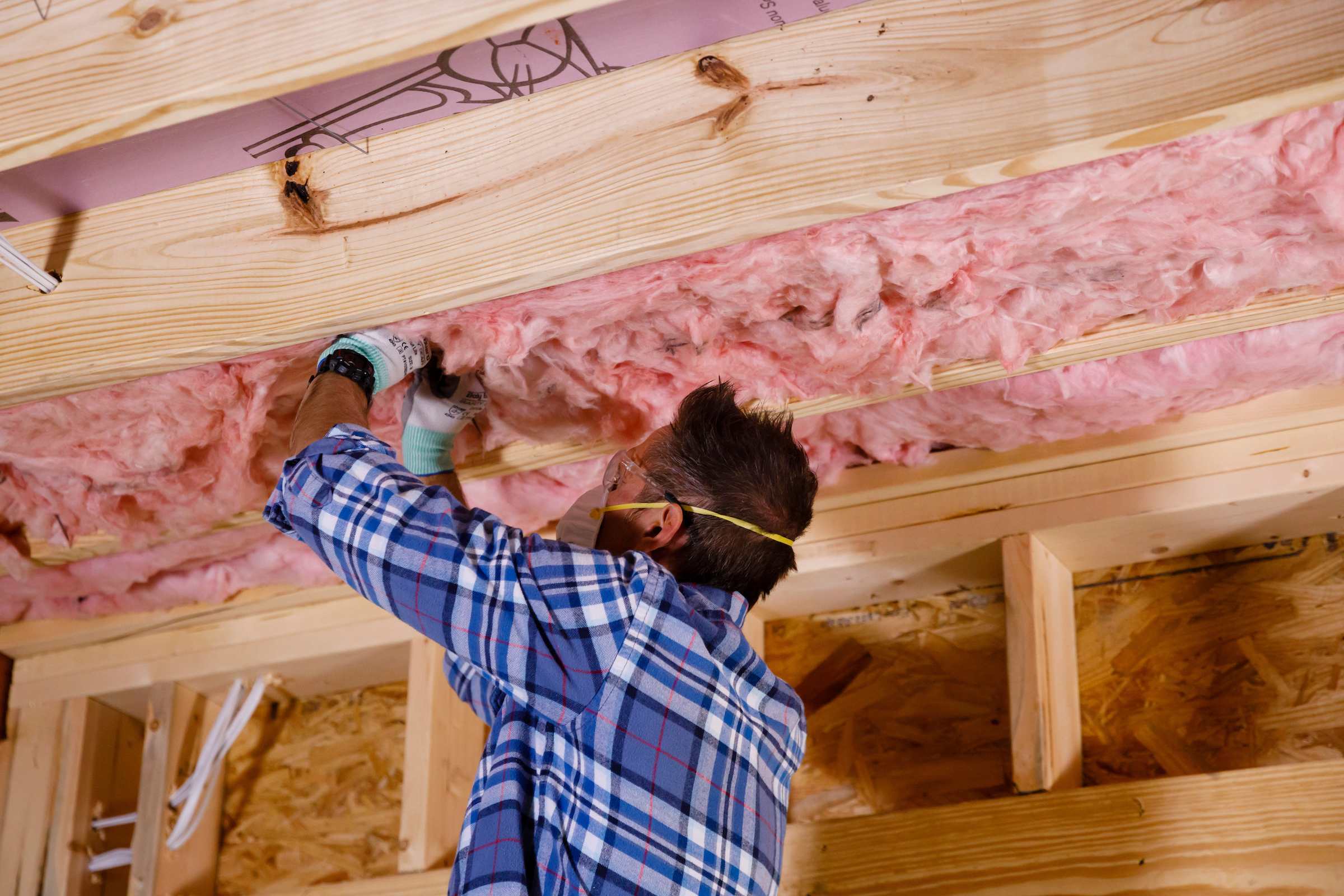 A man installing insulation in a ceiling.